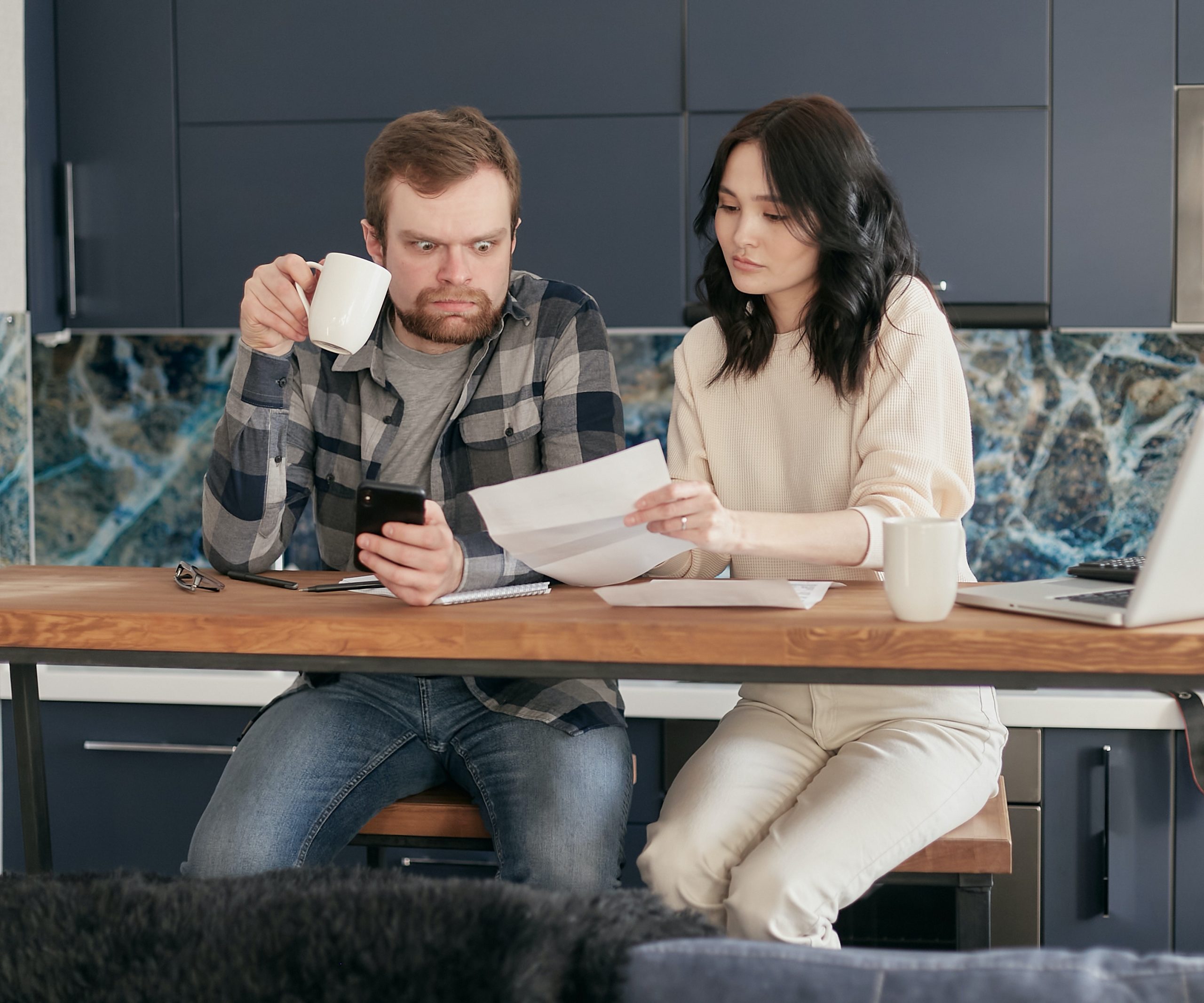 White man and Asian woman sitting at a table reviewing bills. not looking happy