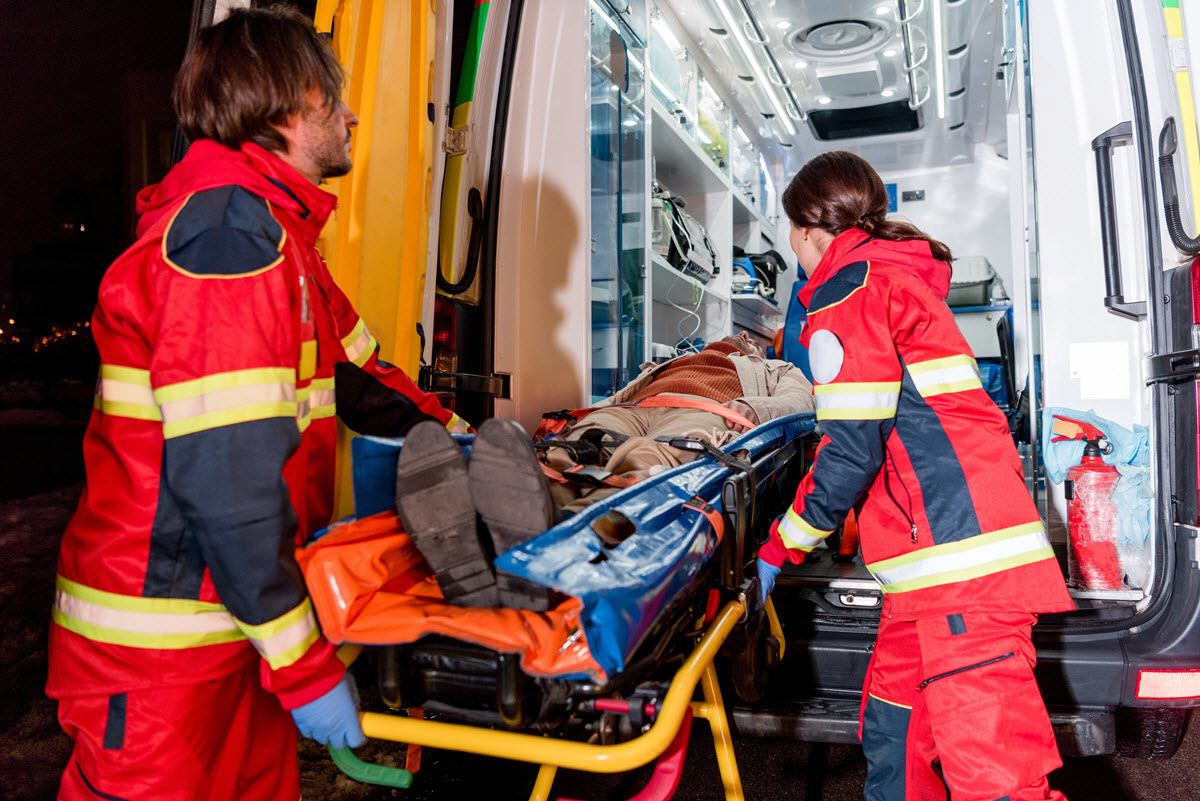 Paramedics lift man into an ambulance